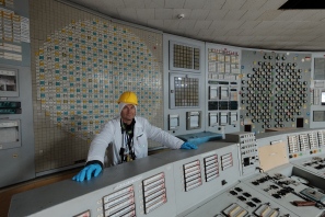 A visitor stands behind A Desk (reactor control engineer's position) in the Unit 2 control room, ChNPP.